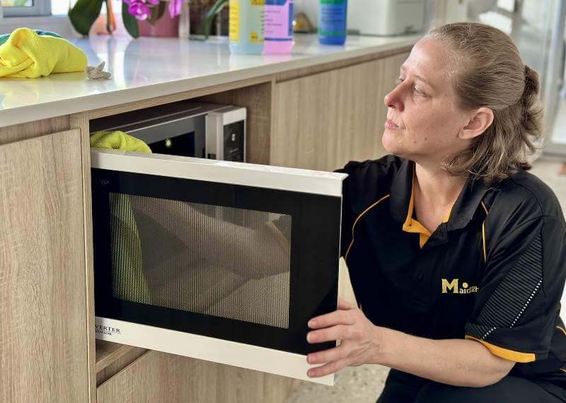 Maid2Match local and insured professional house cleaner cleaning the inside of an oven