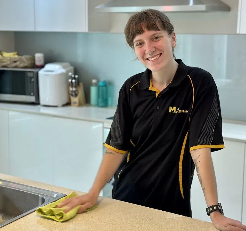 Maid2Match professional house cleaner smiling while cleaning in the kitchen