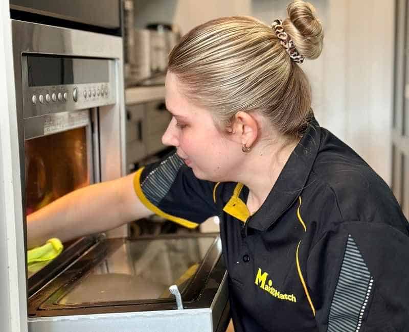 Maid2Match house cleaner cleaning the inside of a microwave oven